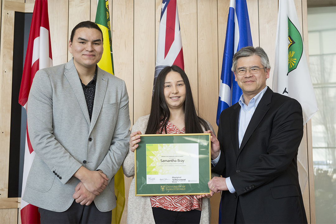 Dallas Fiddler, president of the Indigenous Students' Council (left) and Dr. Andrew Allen, WCVM professor (right) present Samantha Bray (centre) with an Aboriginal Student Achievement Award. Photo by David Stobbe.