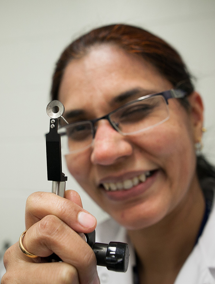 Dr. Aulakh holds up a lung thoracic window, a small tool that was custom built for imaging the lungs of live mice under the intravital microscope. 