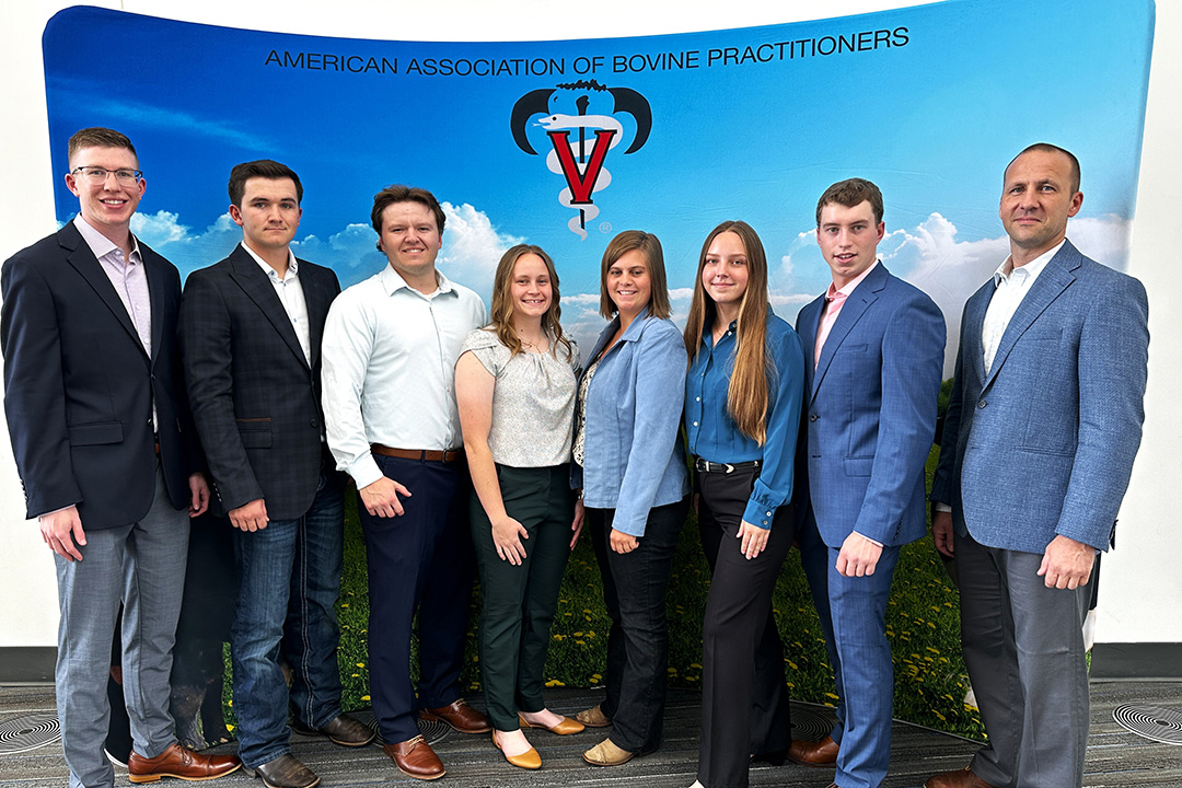 Group of eight people stand in front of a blue banner display