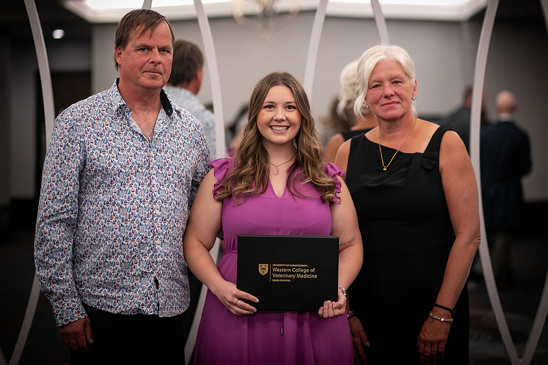 Two donors with a veterinary student (centre) holding an award folder. 